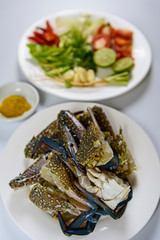 Preparation with raw crab, lemon, onion, pepper, tomato, herbs and spices on white plate, Sea food.