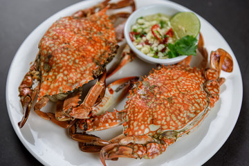 Steamed blue crab on white plate with spicy seafood sauce