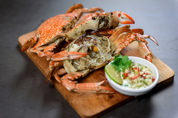 Steamed blue crab on wooden plate with spicy seafood sauce