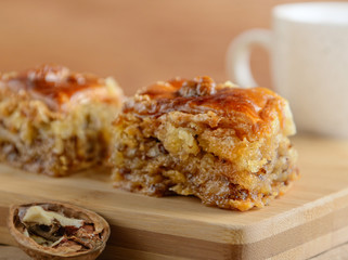 Piece fo baklava on a wooden board with walnut