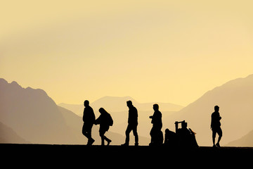 Fototapeta na wymiar Silhouetted people walking on street over sunset sky and high mountains in Antalya, Turkey