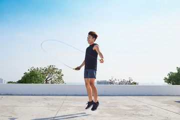 fitness, sport, people, exercising and lifestyle concept - man skipping with jump rope outdoors - obrazy, fototapety, plakaty