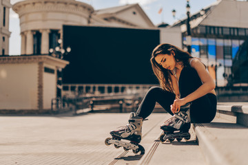 Roller skating woman putting on inline skates for rollerblading