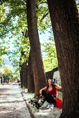 Young woman in sportswear drink water from shaker after roller skating