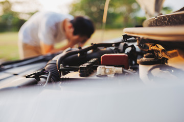 A young man in despair clutched his head, because his car broke down on the road and it is not...