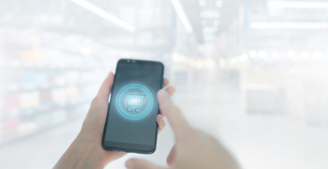 Shopping basket on a mobile phone screen. Woman Hand holding mobile phone on Supermarket blur background