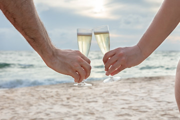 Clinking Glasses Of Champagne In Hands At Beach