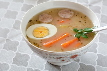 Traditional Polish soup Zurek with white sausage and egg.