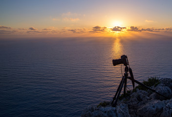 Camera on a tripod isolated in sunrise background. silhouette of camera on tripod with mountains background in sunrise, camera prepared to take photos, tripod.shooting mountains in sunset