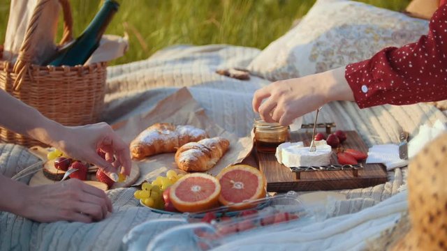 Two women having a picnic - fruits and desserts on the blanket