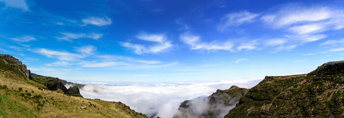Beautiful 180 degree panoramic landscape panorama of the hiking path in the mountains of Madeira at Pico do Areeiro (Arieiro) against blue sky, clouds and sun rays while hiking to Pico Ruivo.