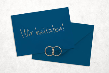Grußkarte mit Nachricht "Wir heiraten!" und zwei Ringe auf weißem Hintergrund