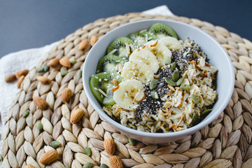 healthy breakfast of oatmeal with kiwi, banana on a wicker napkin and almond