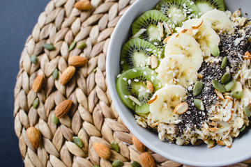 healthy breakfast of oatmeal with kiwi, banana on a wicker napkin and almond