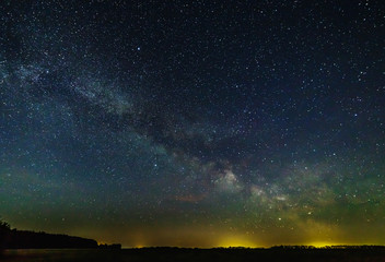 Fototapeta na wymiar Starry sky and the milky way over the meadow and forest.