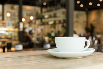Cup of coffee on wooden table in cafe with blurred background.