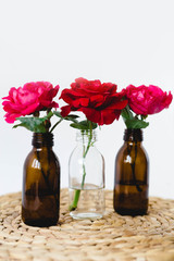 Red roses in glass vases on a wicker napkin on white background