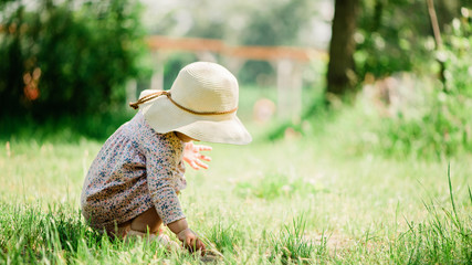 baby girl seating on the grass - summer day of childhood, straw hat, copy space
