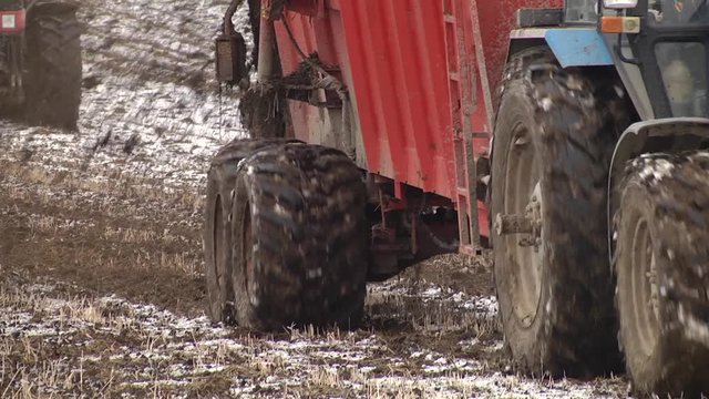 A farmer using a manure spreader behind his tractor to spread an organic mixture of manure and hay on his land for fertilisation. Manure is used as fertilizer in agriculture. Concept: agriculture