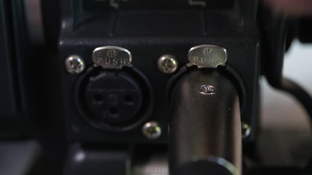 Hand disconnecting and connecting two xlr inputs on professional camera. 4k video macro shot