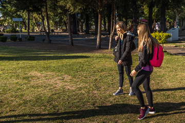 Three young women meet in the park, they greet each other and are happy to meet