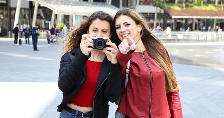 Two girls shooting pictures with a digital camera outdoor in the city