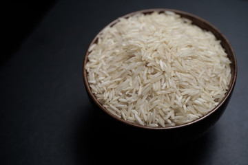 Rice inside wooden bowl on top of black stone plate with wooden matt