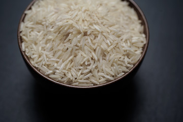 Rice inside wooden bowl on top of black stone plate with wooden matt