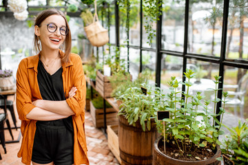 Portrait of a young and confident woman as a business owner of the beautiful greenhouse or flower...