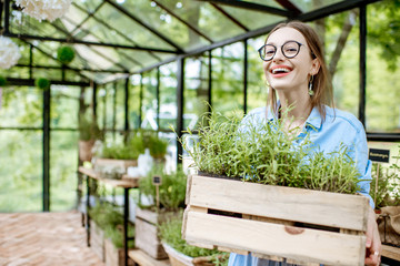 Portrait of a happy woman with wooden box full of herbs in the greenhouse © rh2010