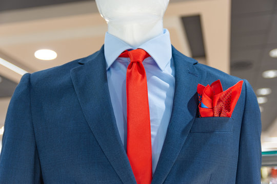 Close up of a mannequin in a fashion store in blue jacket, with a red tie and scarf.