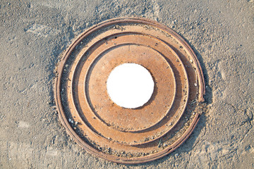 Manhole cast iron heavy brown with a pattern of several rings on the background of concrete screed. In the center of the round white background for photo inscription