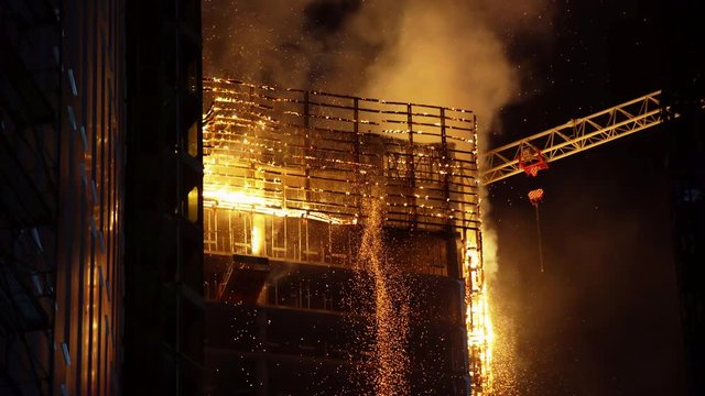 Skyscraper on a construction site with a crane is eaten by the fire during a catastrophic fire