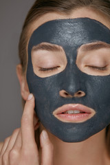 Skin care. Woman face with cosmetic spa clay mask closeup