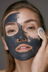 Beauty treatment. Woman taking off mask with cosmetic white pad