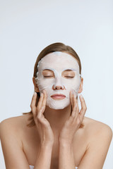 Facial mask. Woman using sheet mask on face skin for spa care
