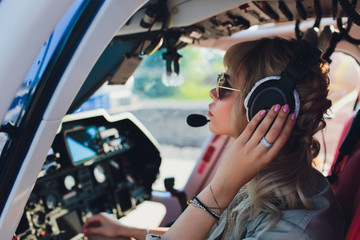 Female pilot in cockpit of helicopter before take off. Young woman helicopter pilot. © Евгений Вершинин