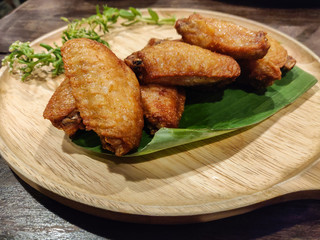 The chicken wings fries on wooden plate.
