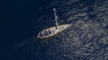 Aerial drone top view photo of sail boat sailing in mediterranean Aegean island of Santorini, Cyclades, Greece