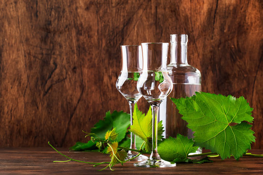 Grape vodka, pisco - traditional Peruvian strong alcoholic drink in elegant glasses on vintage wooden table, copy space