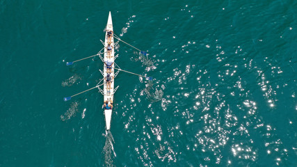 Aerial drone bird's eye view of sport canoe operated by team of young trained athletes in deep blue Aegean sea - obrazy, fototapety, plakaty