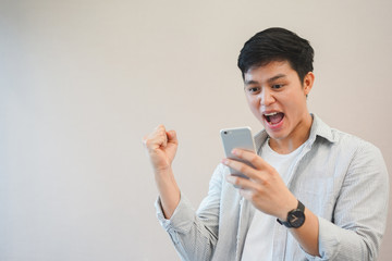 Naklejka premium Close up young asian man raising hand with feeling success and happy after become winner in the online challenge competition , millennial and technology concept 
