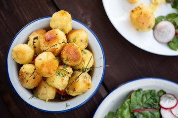 Baked potatoes with herbs on a wooden table in the garden. Delicious vegetarian food outdoors, country lunch.