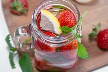 Fruit water with strawberries mint and lemon in the process of cooking, top view.