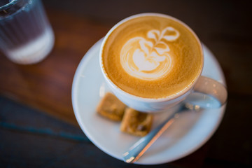 Latte hot coffee with foam milk art on a wooden table