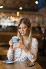 Happy woman enjoying in a cup of coffee in a cafe