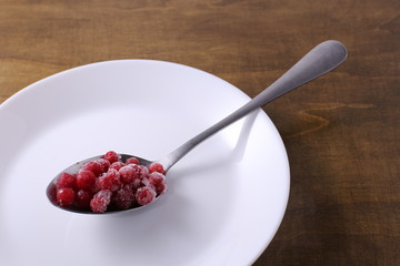 Frozen red currants in spoon. Harvesting fruits for the winter.
