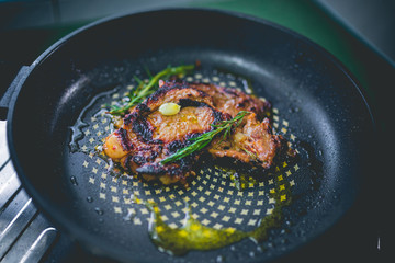 Cooked beef steak with rosemary and garlic inside iron skillet