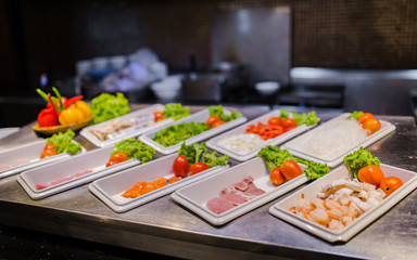 shrimps, pork, beef and salmon on grill station for buffet line