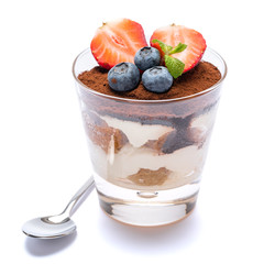 Classic tiramisu dessert with blueberries and strawberries in a glass isolated on a white background with clipping path